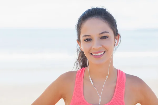 Close-up de sorrir saudável com fones de ouvido na praia — Fotografia de Stock