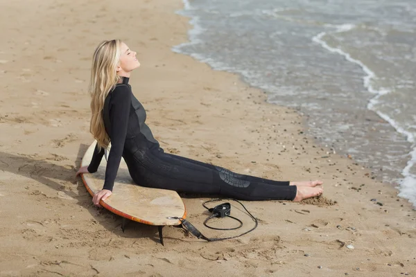 Prachtige blond in nat pak met surfboard op strand — Stockfoto