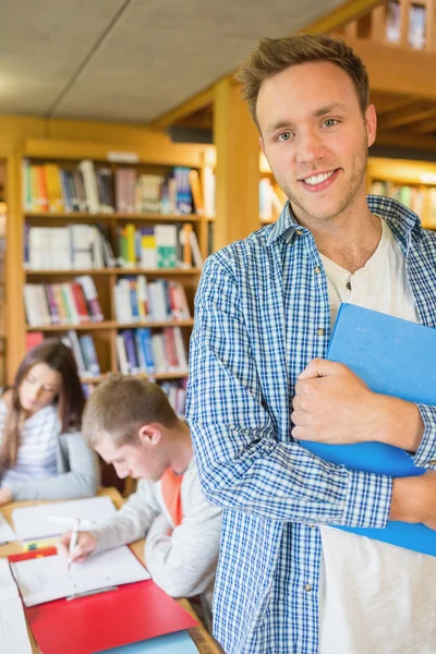 Studente maschio con gli altri in background in biblioteca — Foto Stock