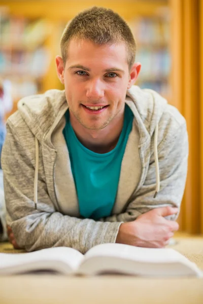 Männlicher Student liest Buch auf dem Boden der Universitätsbibliothek — Stockfoto