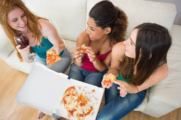 Вид зверху на щасливих друзів, які їдять піцу з вином на дивані — стокове фото