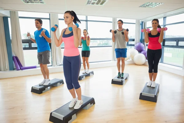 Instructeur avec classe de conditionnement physique effectuant des exercices d'aérobic d'étape avec haltères — Photo