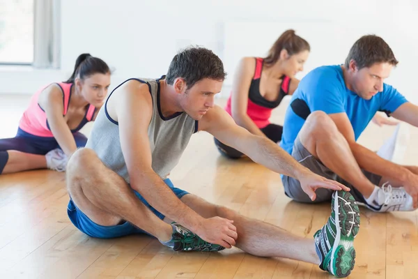 Classe e instrutor alongamento pernas na sala de exercícios — Fotografia de Stock