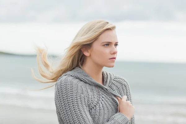 Милая молодая женщина в сером вязаном пиджаке на пляже — стоковое фото