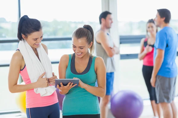 Fitte Frauen am digitalen Tisch mit Freunden, die im Hintergrund chatten — Stockfoto