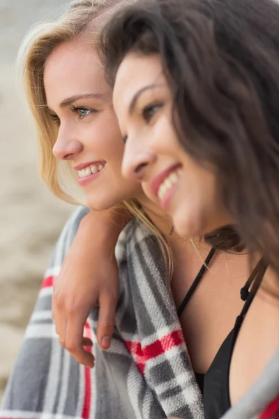 Twee jonge vrouwen bedekt met deken op strand — Stockfoto