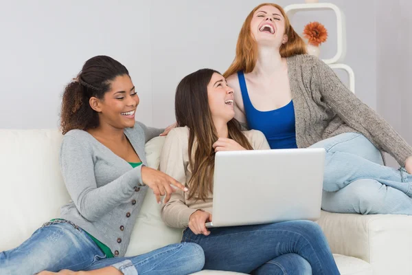 Amigos alegres do sexo feminino usando laptop juntos no sofá — Fotografia de Stock