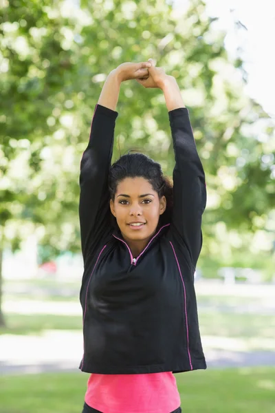 Healthy woman stretching her hands during exercise at park — Stock Photo, Image