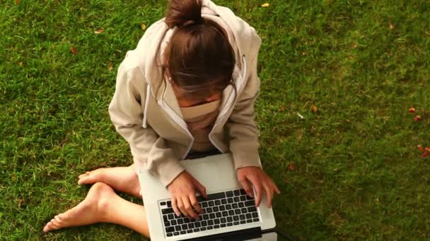 Student arbetar med laptop sitter på gräsmattan — Stockvideo