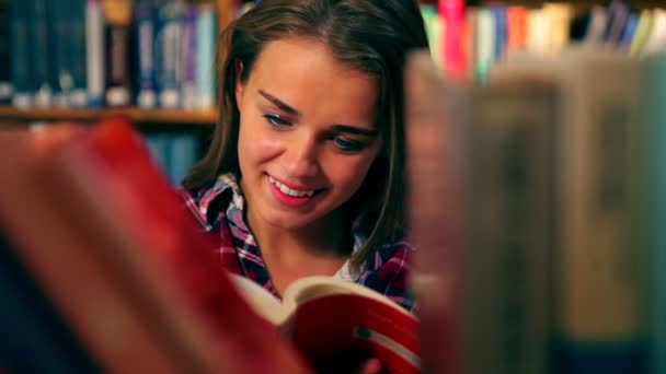 Pretty student reading book standing in the library — Stock Video