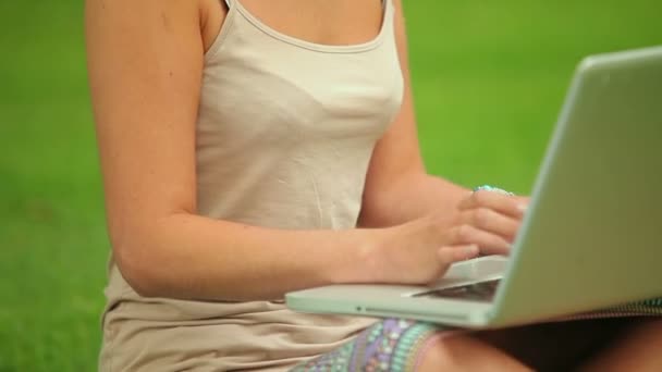 Gelukkig student zittend op het gras met behulp van haar laptop — Stockvideo