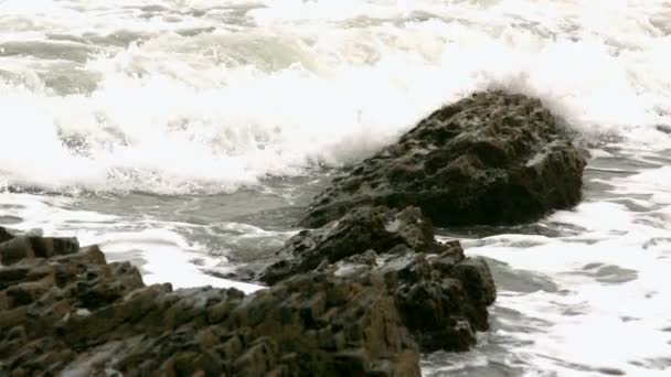Golven die betrekking hebben op rotsen aan de kust — Stockvideo