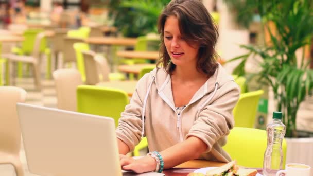 Cheerful student studying while having lunch in canteen — Stock Video