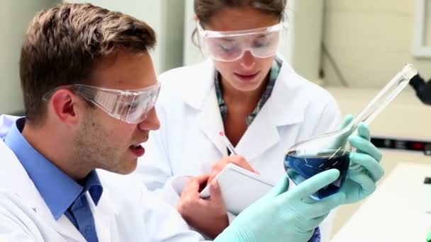Estudiantes de ciencias enfocadas examinando química — Vídeo de stock