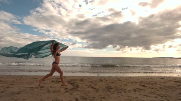 Женщина бежит по пляжу с шарфом — стоковое видео