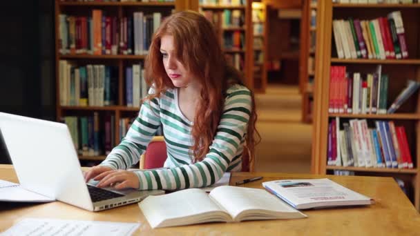 Сфокусированный студент с ноутбуком в библиотеке — стоковое видео