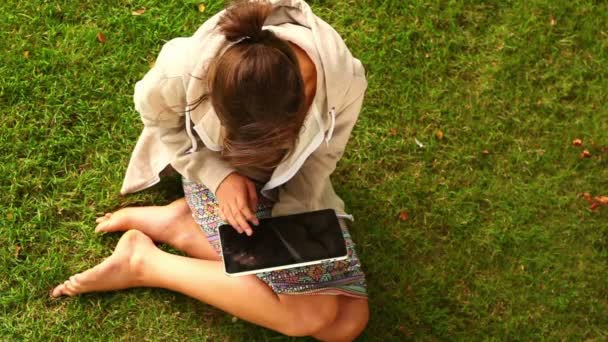 Student working with tablet pc sitting on lawn — Stock Video