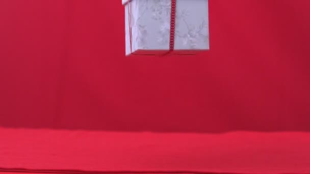 Christmas gift falling and bouncing on red background — Stock Video