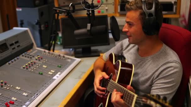Студент поет и играет на гитаре в студии звукозаписи — стоковое видео