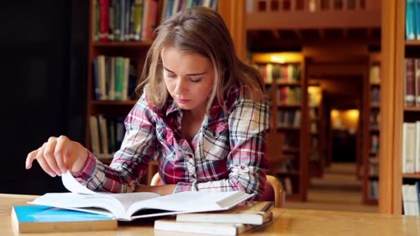 Glad student som studerar på skrivbord i biblioteket — Stockvideo