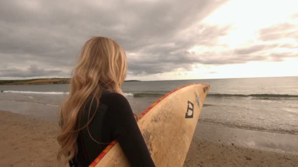 Блондинка держит доску для серфинга — стоковое видео