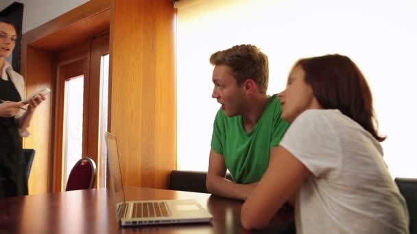 Друзья используют ноутбук и заказывают кофе в столовой — стоковое видео