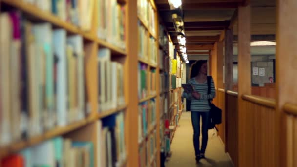 Студент идет через библиотеку — стоковое видео