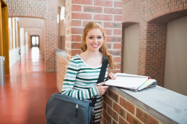 Рыжая студентка улыбается перед камерой в холле — стоковое фото