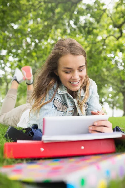 Söt student liggande i gräset som studerar sin tablet PC — Stockfoto