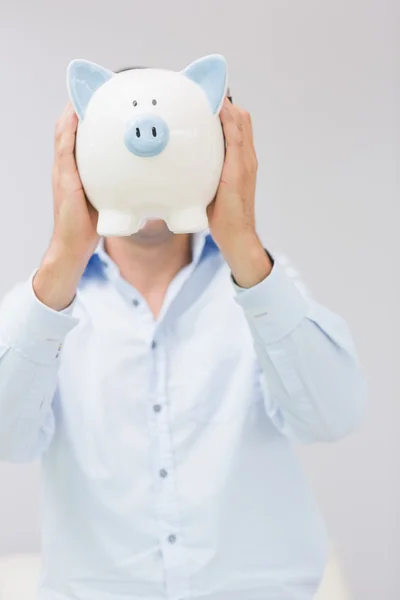Casual man met piggy bank voor zijn gezicht — Stockfoto