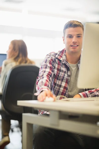 Glückliche Studentin blickt im Computerraum in die Kamera — Stockfoto