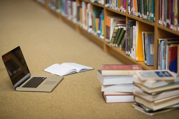 Laptop e livros no chão da biblioteca — Fotografia de Stock