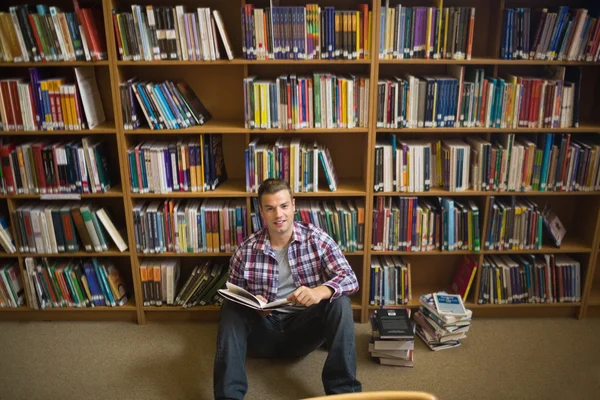 Όμορφος νεαρός φοιτητής κάθεται στο πάτωμα βιβλιοθήκη ανάγνωση βιβλίων — Φωτογραφία Αρχείου