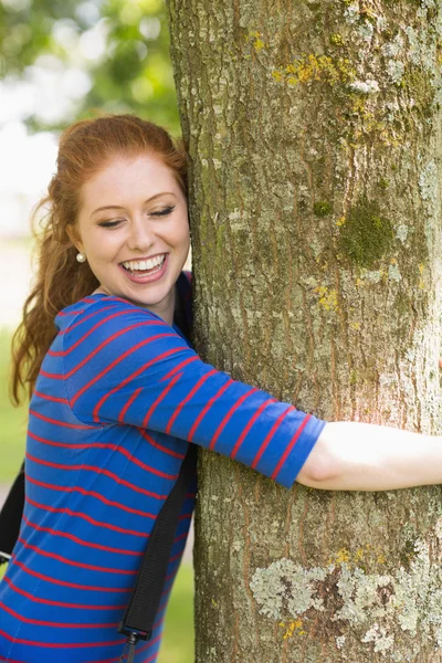 Laughing redhead hugging a tree — Stock Photo, Image