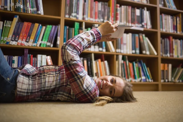 Estudante bonito deitado no chão da biblioteca livro de leitura — Fotografia de Stock