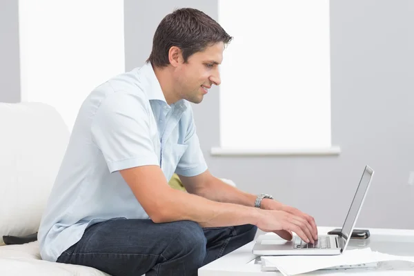 Zijaanzicht van lachende man met laptop thuis — Stockfoto