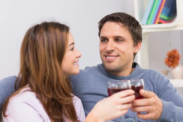 Sorrindo jovem casal com copos de vinho sentado em casa — Fotografia de Stock