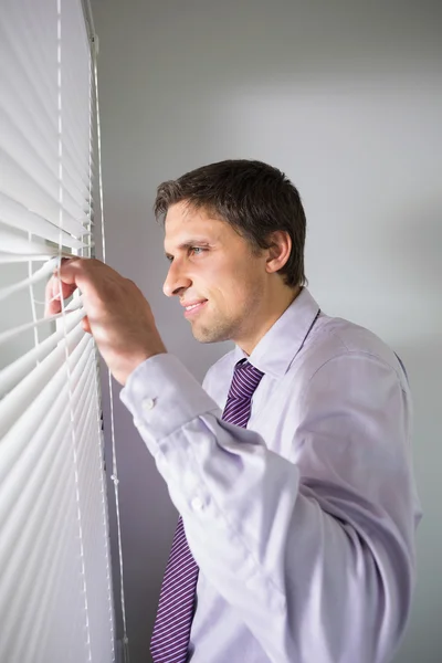 Empresário espreitando cortinas no escritório — Fotografia de Stock