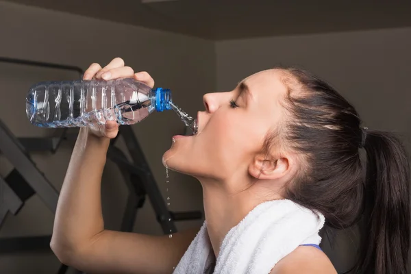 Primer plano de una joven bebiendo agua en el gimnasio — Foto de Stock