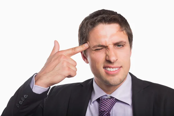 Businessman holding fingers against temple in gun gesture — Stock Photo, Image