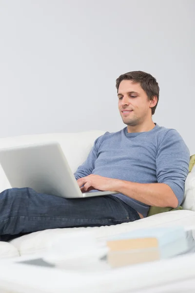 Hombre joven relajado usando el ordenador portátil en la sala de estar —  Fotos de Stock