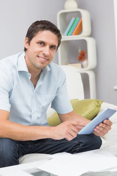 Uśmiechnięty mężczyzna z rachunków za pomocą cyfrowego tabletu w salonie — Zdjęcie stockowe