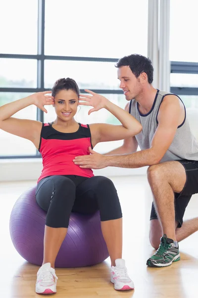 Trainerin hilft Frau bei Bauchkrämpfen auf Fitnessball — Stockfoto