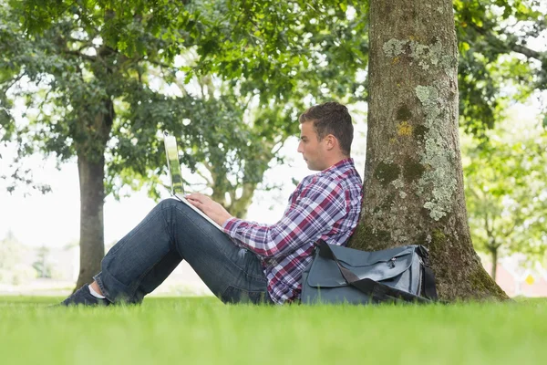 Junger Student benutzt seinen Laptop, um draußen zu lernen — Stockfoto
