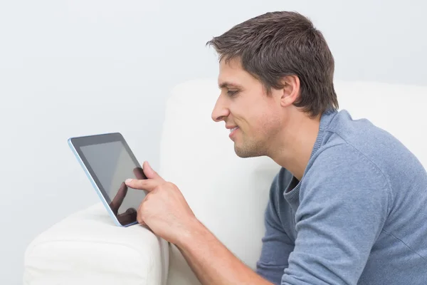 Jeune homme souriant utilisant une tablette numérique dans le salon — Photo