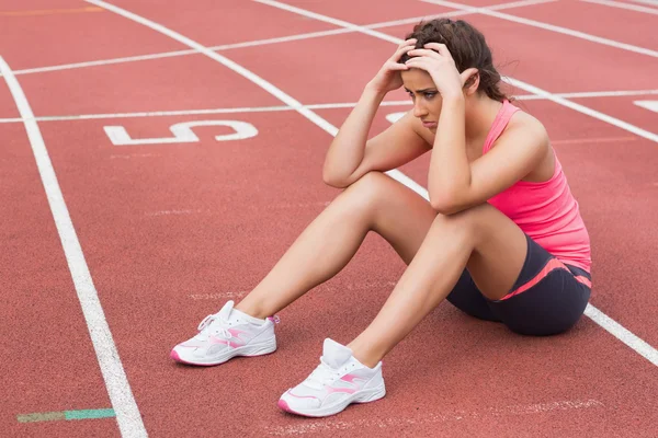 Sportliche Frau sitzt auf der Laufstrecke — Stockfoto