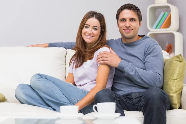 Relaxed couple sitting on sofa at home — Stock Photo, Image