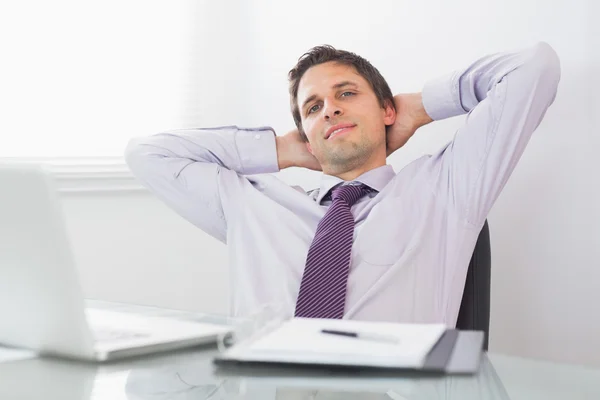 Hombre de negocios relajado con las manos detrás de la cabeza en la oficina — Foto de Stock