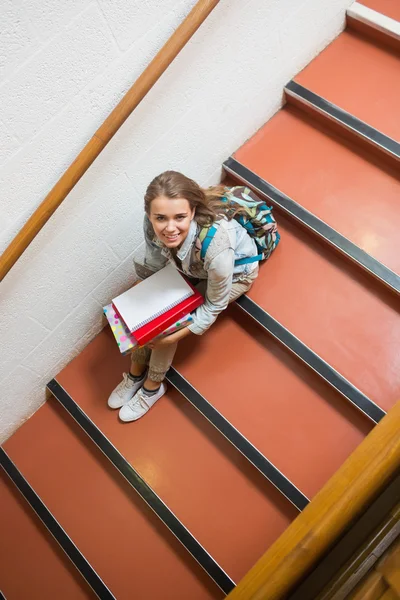 カメラにまで笑って階段に座っている若い学生 — ストック写真