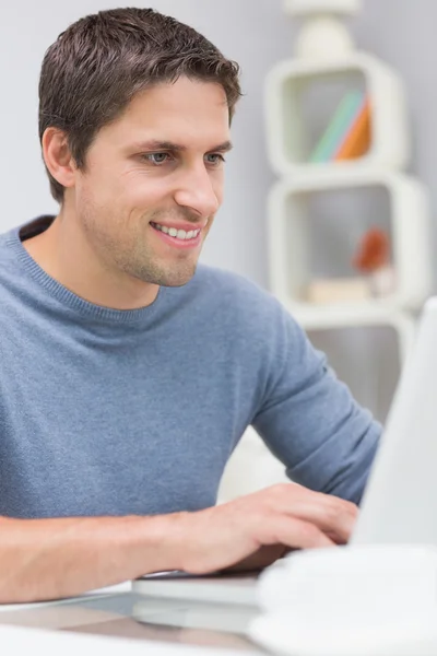 Sonriente joven utilizando el ordenador portátil en la sala de estar — Foto de Stock